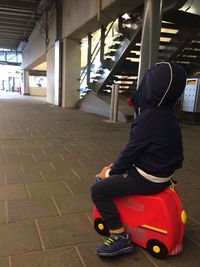 Low section of man sitting on railroad station