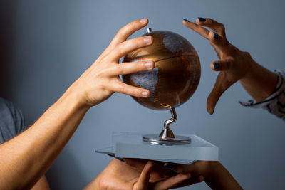 Close-up of people holding globe over blue background