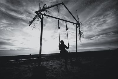 Silhouette man on field against sky during sunset