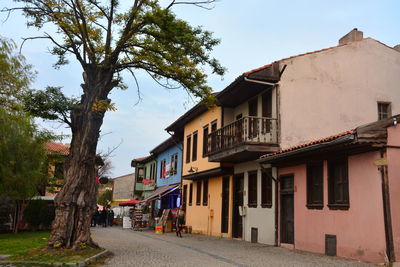 Houses by road amidst buildings in city against sky