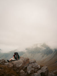 Man sitting on rock against mountain range