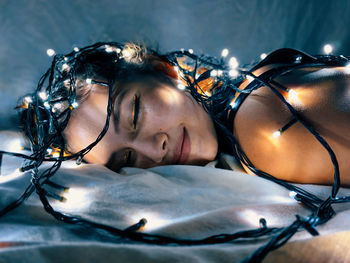 Smiling girl lying down on bed with lighting equipment