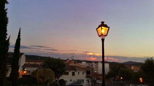 Illuminated street light against sky at night