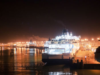 Illuminated harbor against sky at night