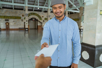 Smiling man receiving envelope in mosque