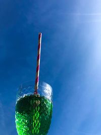 A glass of woodruff lemonade with a straw in the blue sky