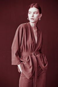 Portrait of young woman standing against red background