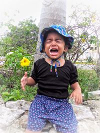 Portrait of happy boy standing against trees