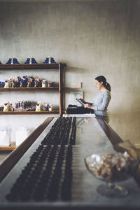 Side view of female owner using tablet computer at counter in store