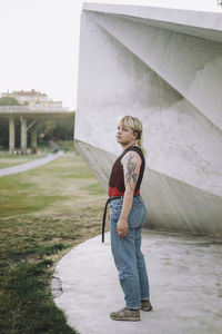 Side view of non-binary person standing near wall at park