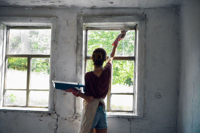 Rear view of woman standing by window