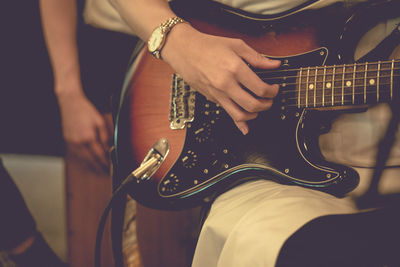 A musician playing guitar at night with warm-toned noise.