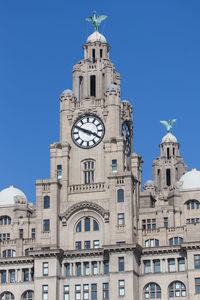 Low angle view of clock tower against clear blue sky