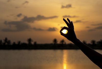 Silhouette person against orange sky during sunrise