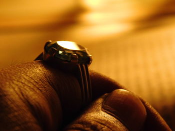 Cropped hand wearing diamond ring in illuminated room