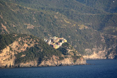 Scenic view of sea by mountain against clear sky