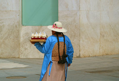 Rear view of woman standing against wall