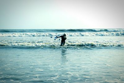 Silhouette man standing in sea against clear sky