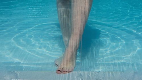 Low section of person standing in swimming pool