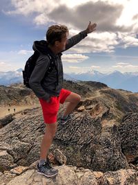 Rear view of boy on rock against sky