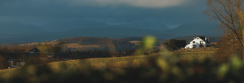 Panorama of field and building against rolling hills