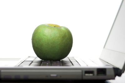Granny smith apple on laptop against white background