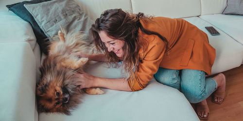 Full length of woman lying down on sofa with dog at home