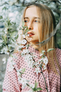 Portrait of young woman standing against plants
