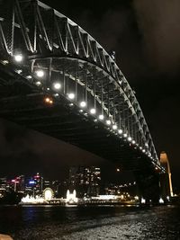 Low angle view of illuminated bridge over river at night