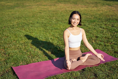 Portrait of young woman sitting on field