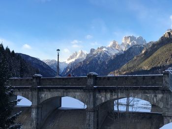 Arch bridge over snowcapped mountains against sky