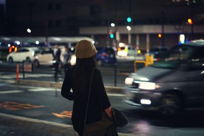 Rear view of woman walking in city at night