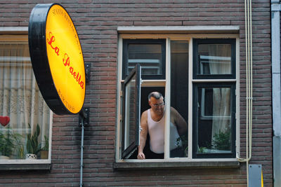 Portrait of shirtless man standing against window in building