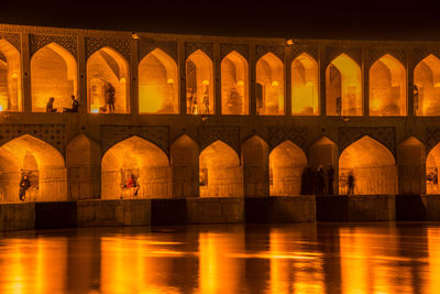 Arch bridge over river in city at night