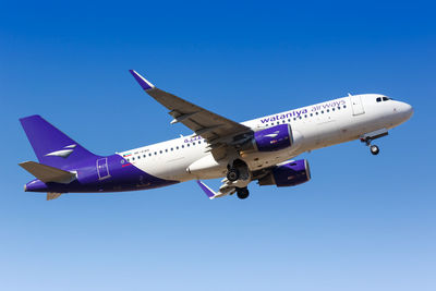 Low angle view of airplane flying against clear blue sky