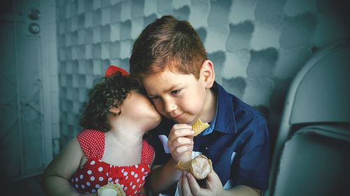 Girl kissing brother while having ice cream at home