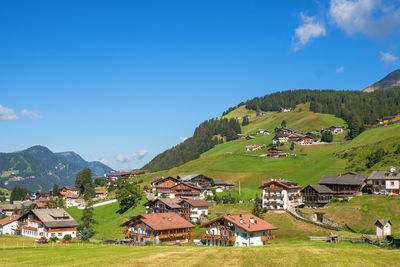 Houses on field by buildings against sky