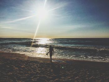 Silhouette man standing on beach against sky during sunset