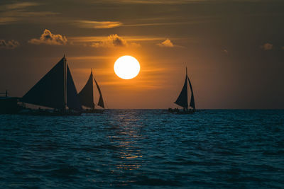 Sailboat sailing on sea against sky during sunset