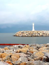 Stone wall by sea against sky