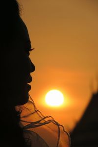 Close-up portrait of silhouette woman against orange sky