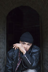 Portrait of confident man in hat sitting amidst walls