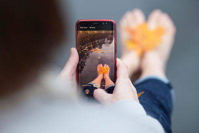 Midsection of woman photographing with mobile phone