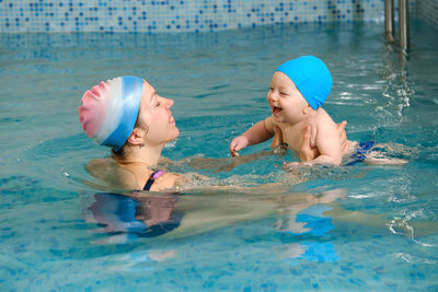 Baby boy trained to swim in water child with trainer playing having fun healthy family with infant