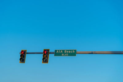 Low angle view of road sign against clear blue sky