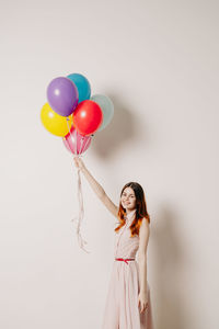 Woman holding colorful balloons against white background