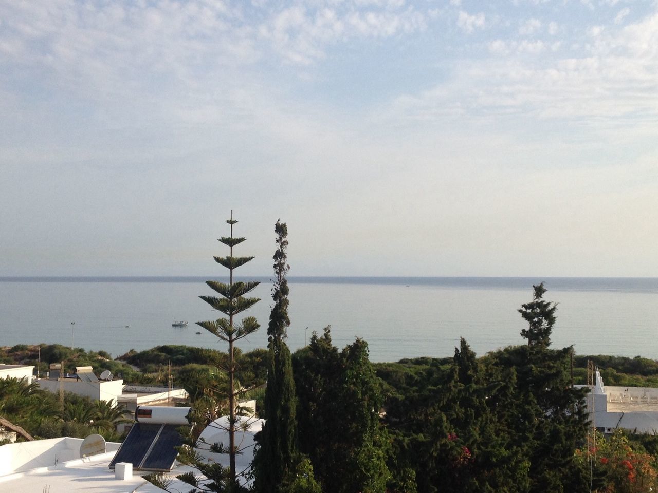 sea, horizon over water, sky, water, building exterior, tree, built structure, architecture, beach, growth, nature, high angle view, plant, beauty in nature, house, palm tree, day, cloud - sky, scenics, tranquil scene