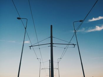 Low angle view of electricity pylon against blue sky