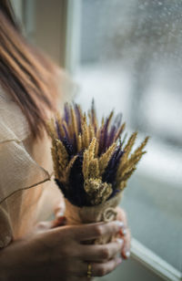 Midsection of woman holding plant by window