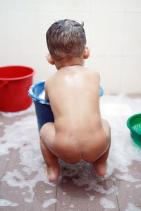 Rear view of naked baby boy taking bath in bathroom